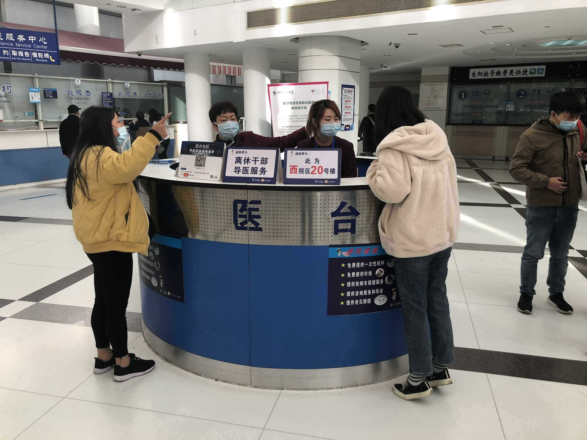 导诊台前,工作人员为患者指引方向.