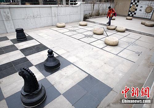 资料图：2012年3月1日，天津街头摆出巨大的棋盘，一边是中国象棋，另一边则是国际象棋，怪异的棋局吸引一位游客驻足。中新社记者 刘关关 摄