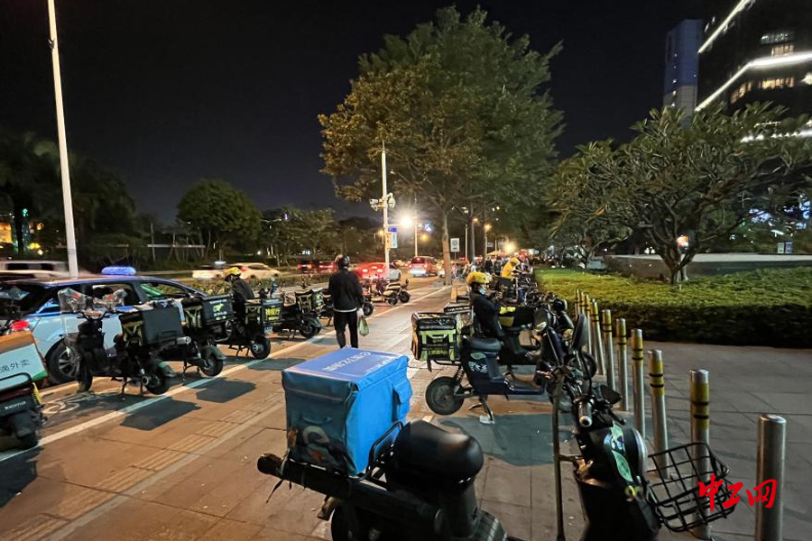 图为深圳夜晚的街道，道路两旁停满了等待接送外卖的车辆和配送员，他们依旧努力地在为这个城市服务着。中工网 王天玥摄