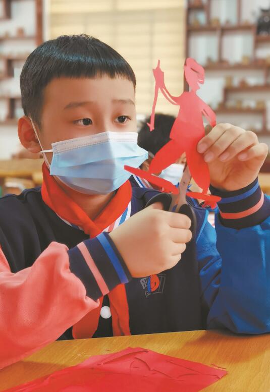 老师正在指导学生剪纸.孩子们展示自己创作的作品.