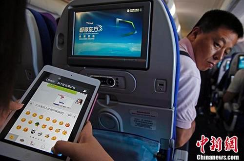 图为2014年7月23日，旅客在东航实际承运的航班上使用平板电脑(Pad)，进行空地互联微信聊天。 中新社记者 殷立勤 摄