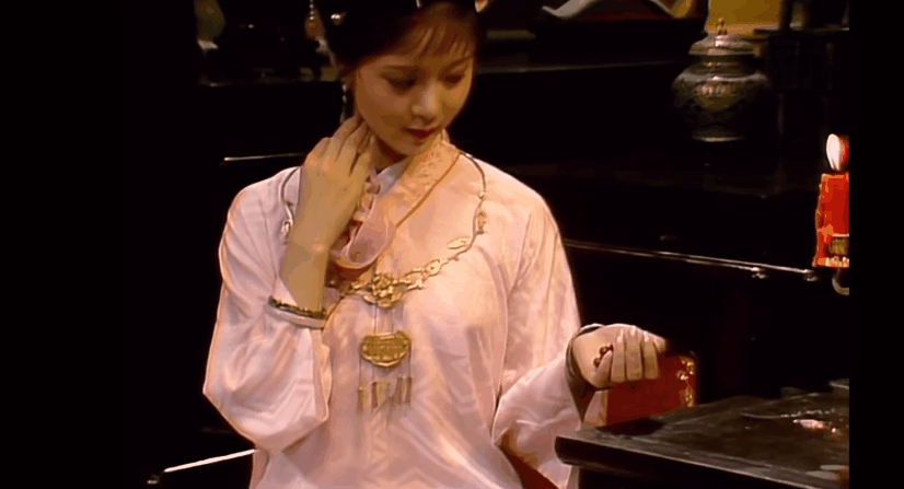 宝玉要看宝钗手上的红麝串,她褪下来后放在桌上,再轻轻起身避在一旁.