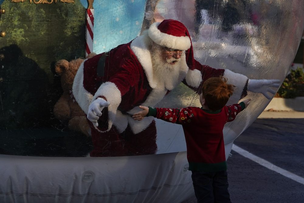 去年，商场里的圣诞老人只能隔着气球与孩子们拥抱  图源：彭博社