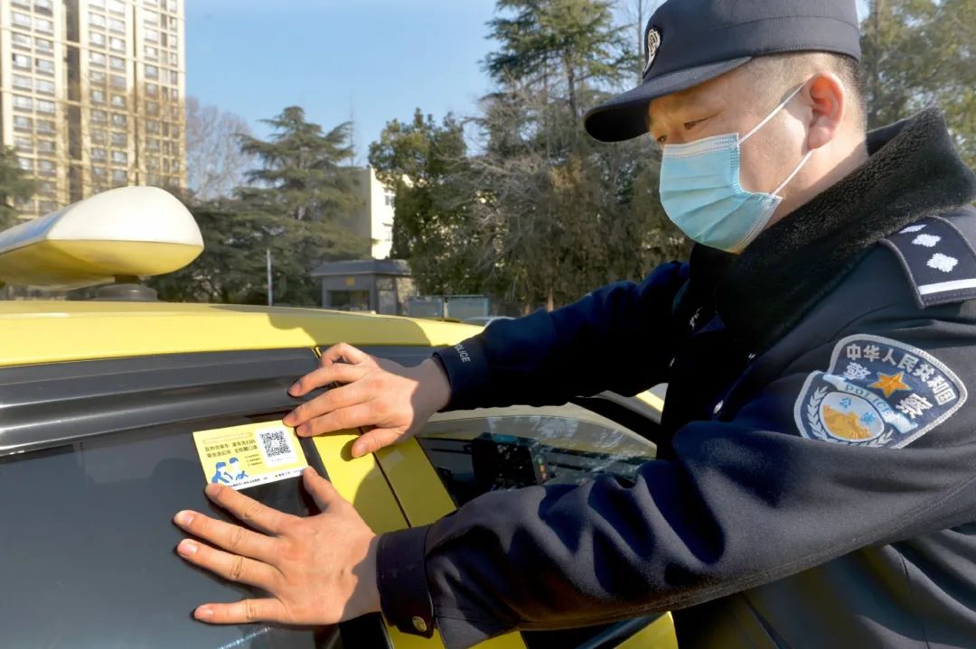 交通执法人员为巡游出租汽车现场张贴行程信息采集二维码.