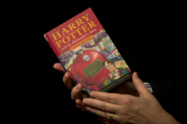 2013年5月20日，在英国首都伦敦	
，一名苏富比拍卖行的工作人员手持一本带有作者J·K·罗琳亲笔批注的首版《哈利·波特与魔法石》小说。（新华社/美联）