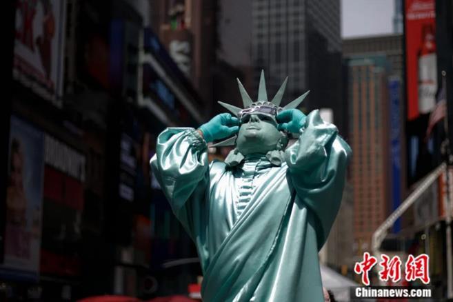 2017年8月，纽约时报广场上自由女神表演者观看日食。中新社记者 廖攀 摄