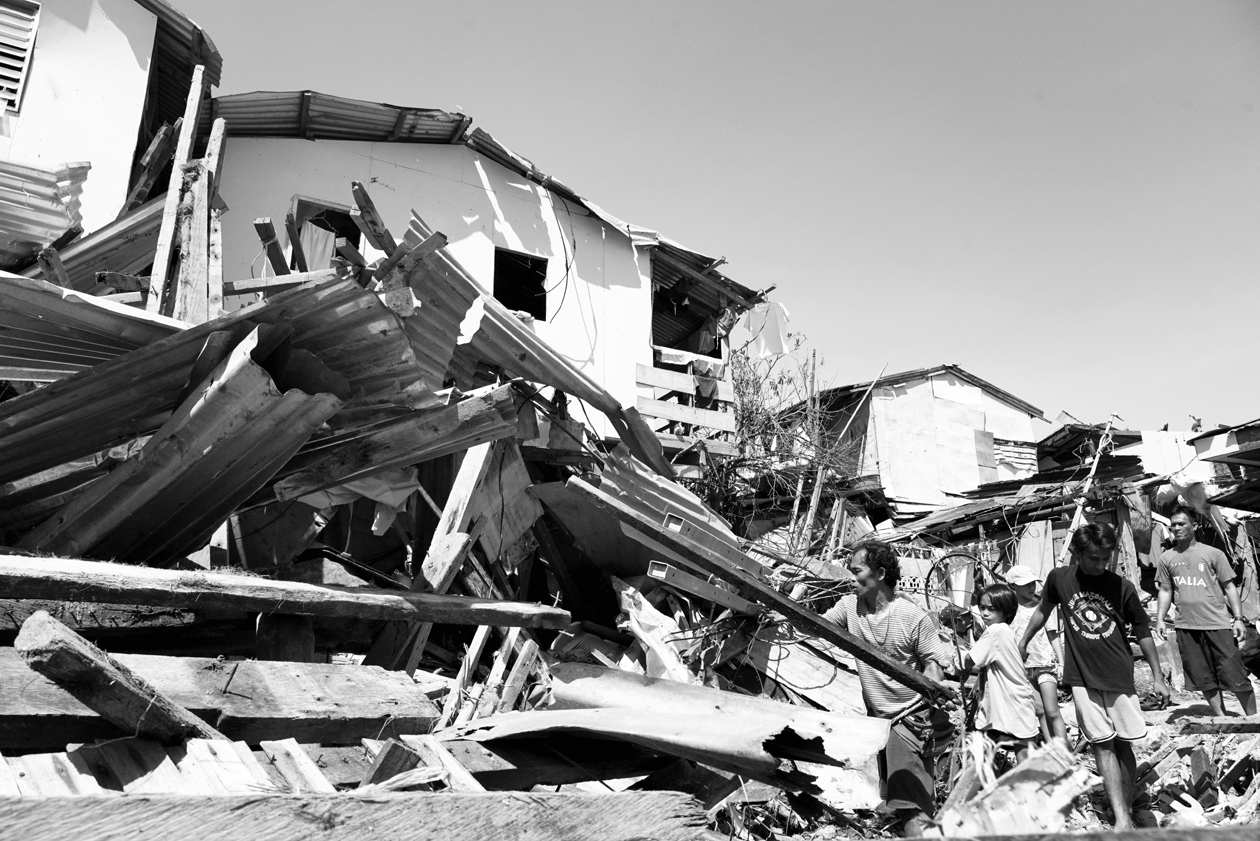 12月18日,人们在菲律宾宿务省的房屋废墟中寻找物品.