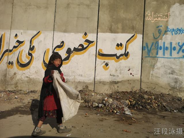 喀布尔机场外墙前，一名拾荒女童在此徘徊。当前阿富汗街头流浪人员中，有大量是妇女、儿童、残疾人和吸毒者。汪段泳摄
