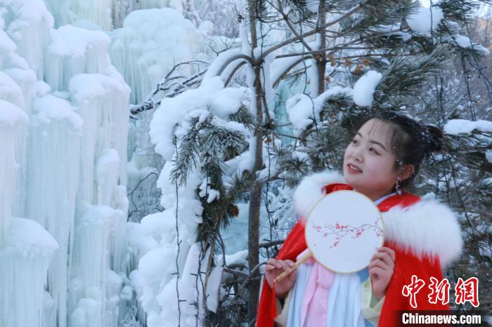 图为身着汉服的游客在冰瀑前拍照留念。张婧 摄