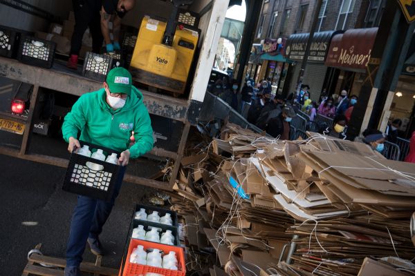 资料图：在美国纽约一个食品发放点，工人搬运免费发放的牛奶。（新华社）