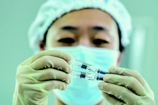 工作人员在国药集团中国生物北京生物制品研究所的新冠病毒灭活疫苗分包装车间内检查产品包装质量(2020年12月25日摄)。新华社记者张玉薇摄
