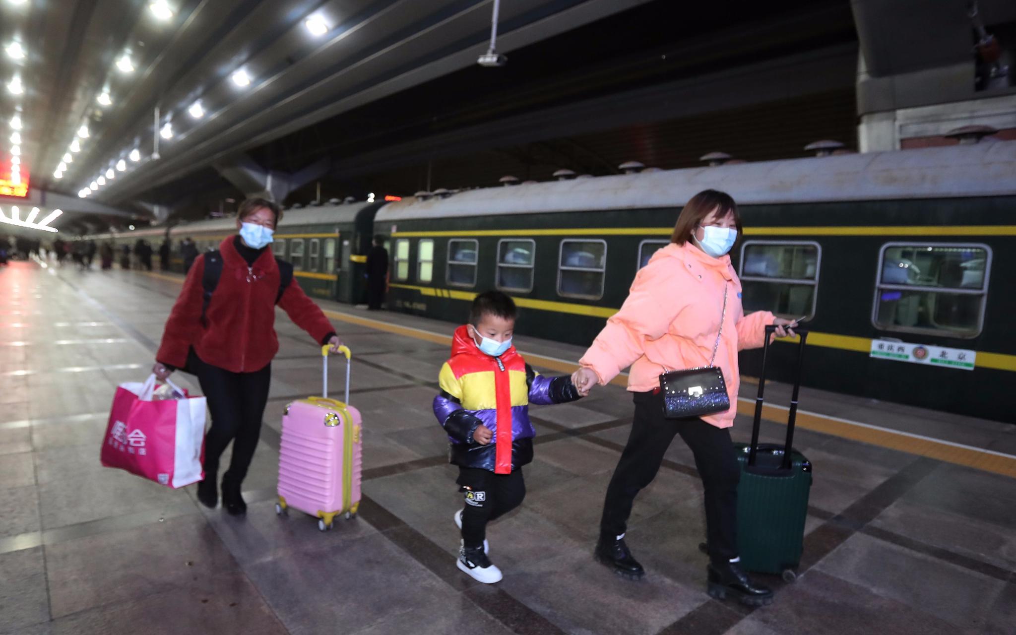 今天凌晨,北京站开出春运首班临客,旅客拖着行李箱准备上车。新京报记者 王贵彬 摄