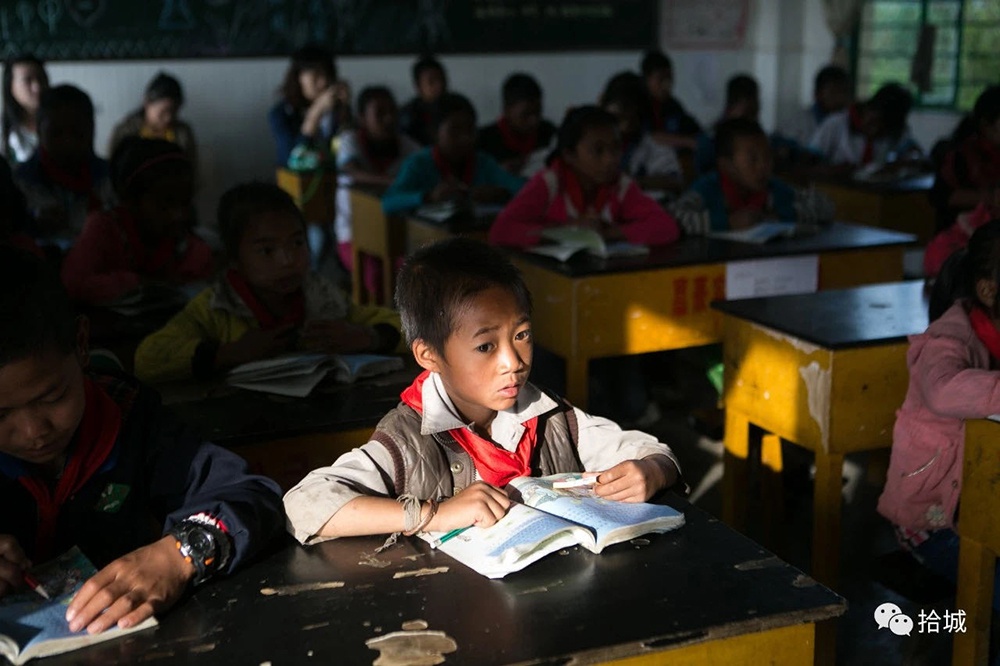 临沧（云南）-2015年6月2日，一名佤族小朋友在晨读时走神。拾城 贾亚男