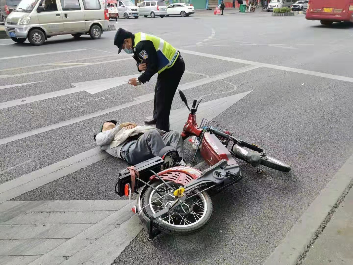 画面中,一名老人仰面倒在了马路一侧,所骑的电动自行车倒在一旁,而在