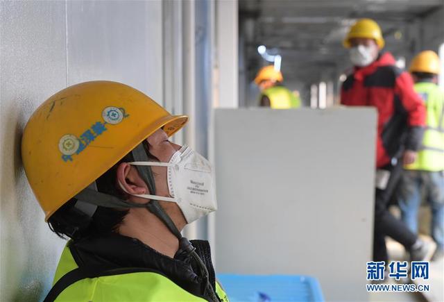2月3日，一名疲惫的工人在武汉火神山医院工地一处正在施工的病房外小憩。 新华社记者 李贺 摄