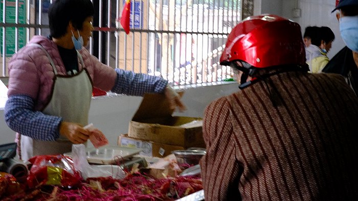 市场里的年货摊位，一位阿婆正在挑选腊肉和腐竹。图片来源：史子杨/摄