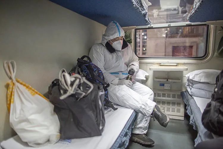 1月28日0时26分,一位乘客戴着口罩,身穿防护服坐在卧铺车厢.