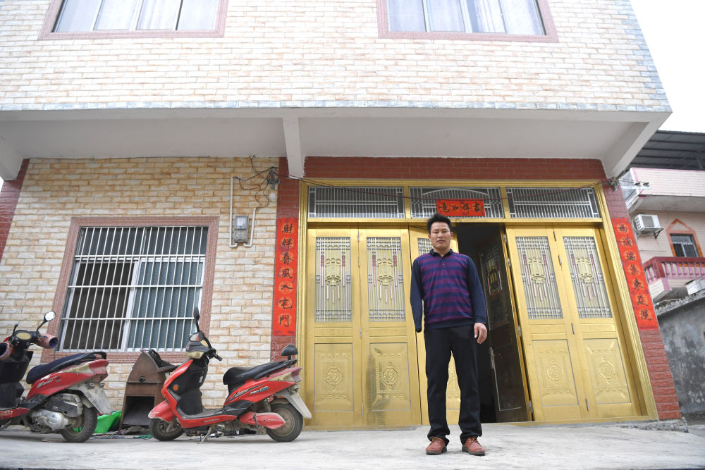 韦寒贵在自家新房前留影（2月3日摄）。新华社记者 周华 摄