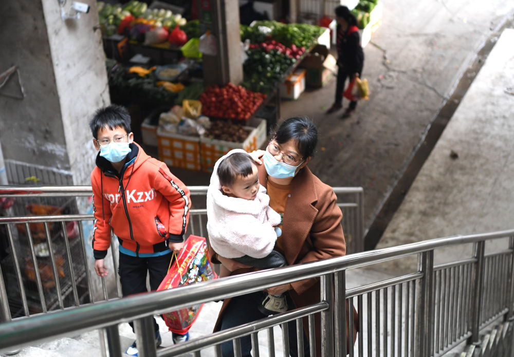 韦寒贵的妻子韦丽妹带着两个孩子从大化瑶族自治县县城菜市场旁经过（2月3日摄）。新华社记者 周华 摄