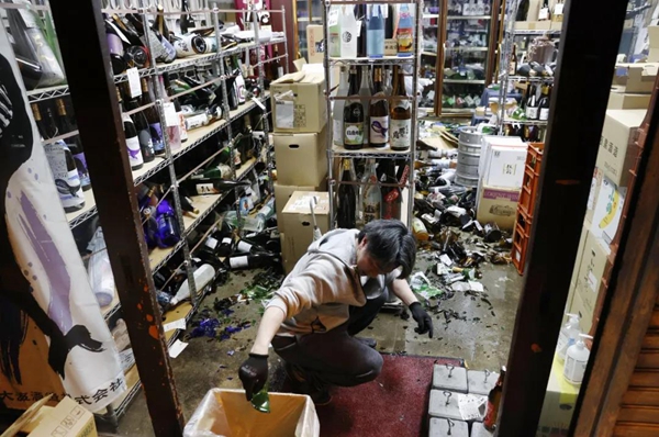 2月13日，在日本福岛县福岛市，酒铺的店主在清理地震中掉落的酒瓶。新华社/共同社