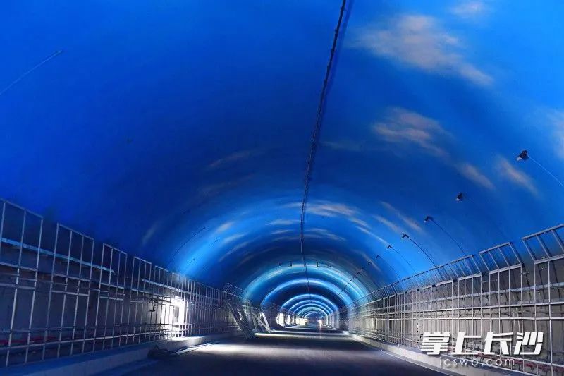 目前,麓景路南延线工程隧道顶部蓝天白云彩绘已喷涂完毕,正在进行防