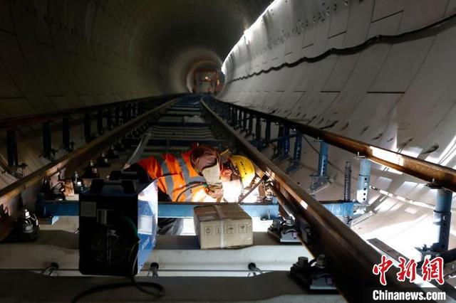 2021年2月23日,工人们正在北京地铁17号线南段隧道内进行钢轨铺设作业。 富田 摄