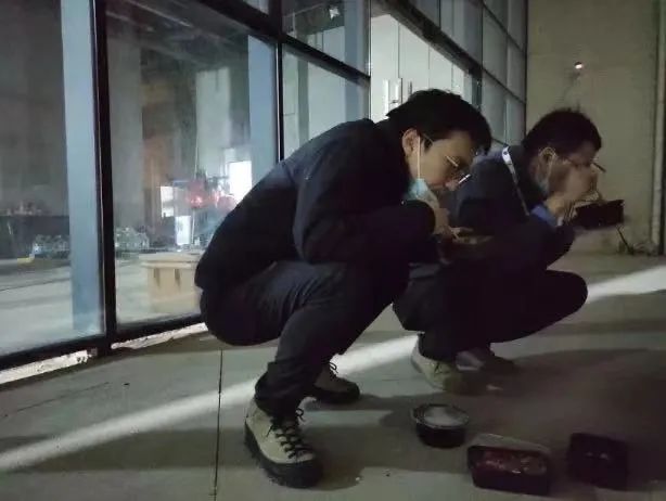 ▲2020年2月5日，武汉“火眼”实验室施工场地外，朱师达（左）正抓紧时间吃饭。华大基因供图