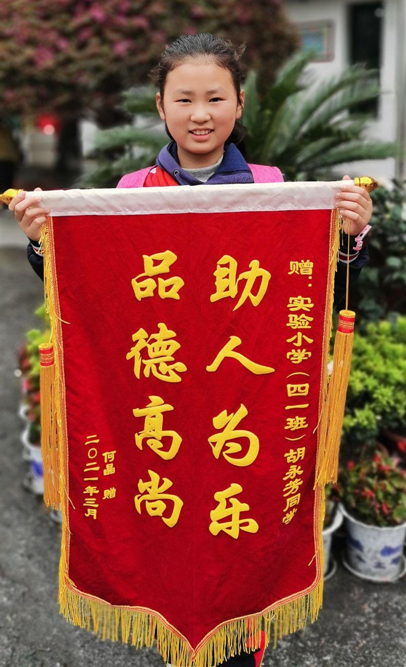 事后,何女士来到实验小学将一面锦旗送到学生胡永芳手上,再次向她的