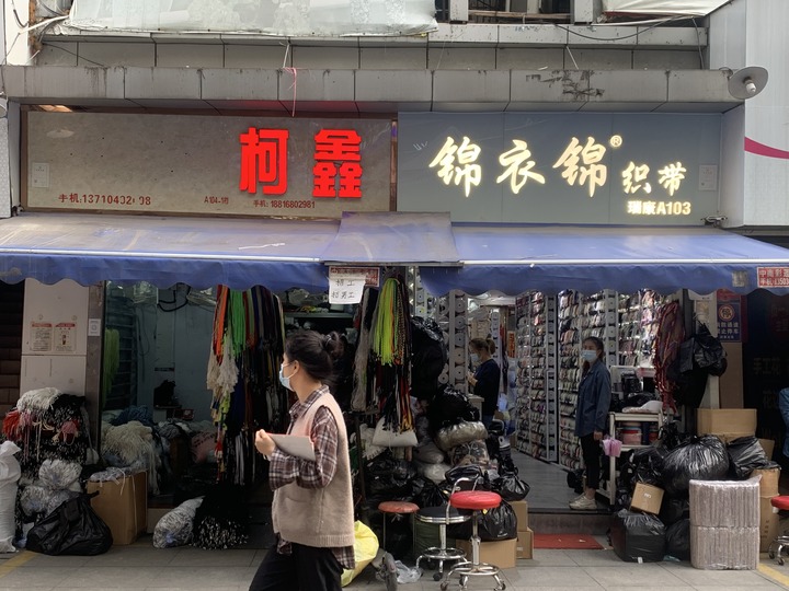 ↑广州中大布匹市场内，许多服装店、布料店等门外挂出牌子招工人。