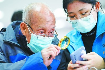 北京外国语大学的志愿者在“科技助老”活动中为老人讲解智能手机使用方法。新华社发