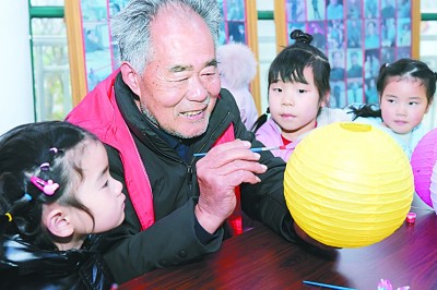 江苏省海安市胡集街道田庄村的空巢老人与留守儿童一起制作花灯。光明图片