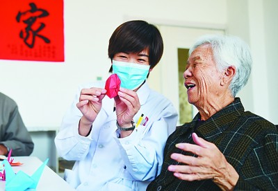 河北沧州青县康泰养老护理中心护理人员与老年人一起折纸。新华社发