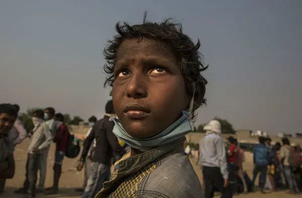 ▲资料图片：在印度新德里郊区的加济阿巴德，一名儿童排队等待登上返乡大巴。新华社发