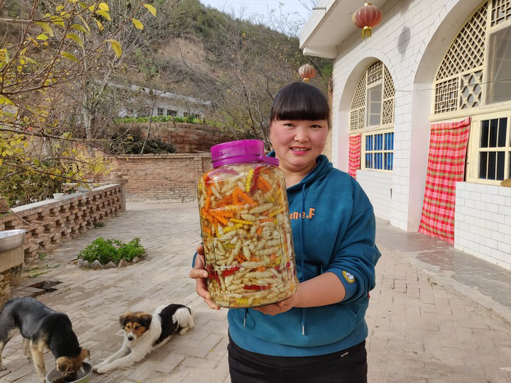 "陕北霞姐"王敏在自家窑洞前,手里拿着她自制的泡菜.