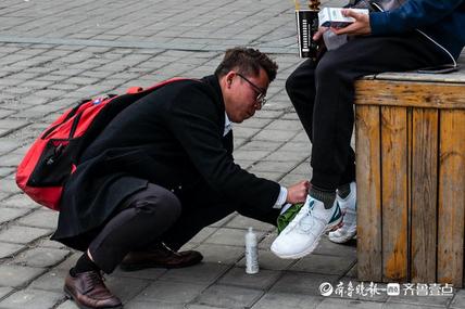 街头屈身下蹲擦鞋演示做营销的小伙