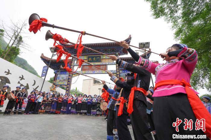 图为布依族同胞在寨门吹奏唢呐和长号,欢度传统节日"三月三".