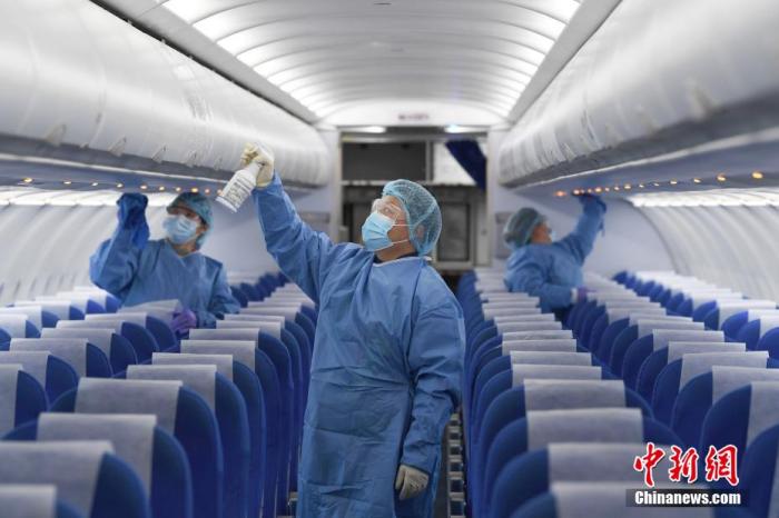 图为1月23日，东航地服人员在对飞机的客舱喷洒专业的消毒液，对小桌板、舷窗等部位进行专业的消毒擦拭。 张大岗 摄