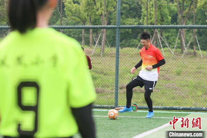 图为东亚足球四强赛冠军成员杨智在足球场上给小运动员示范动作。　刘力鑫 摄