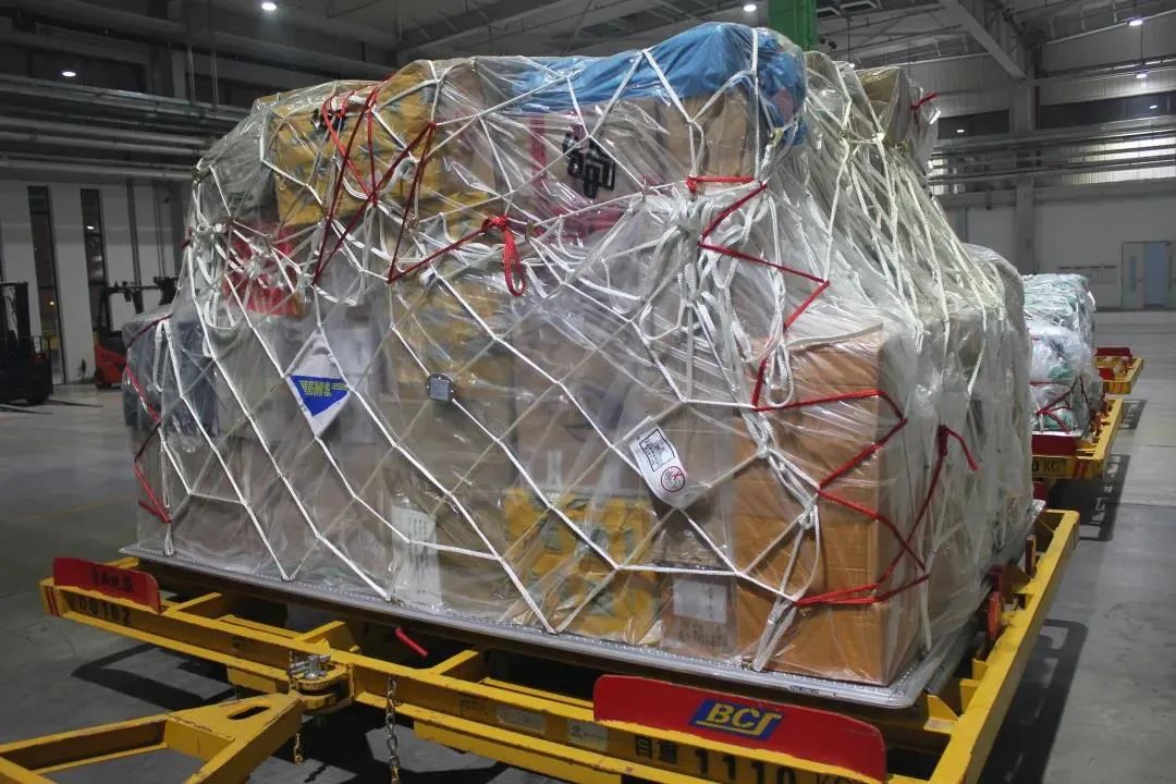 站一派"热火朝天"的繁忙景象,一件件打包好的邮件完成安检后,通过打板