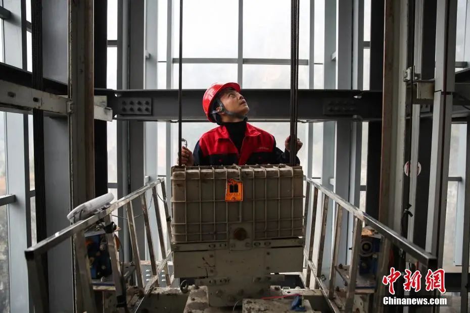 资料图：维保人员在电梯轿顶检修。中新社记者 瞿宏伦 摄