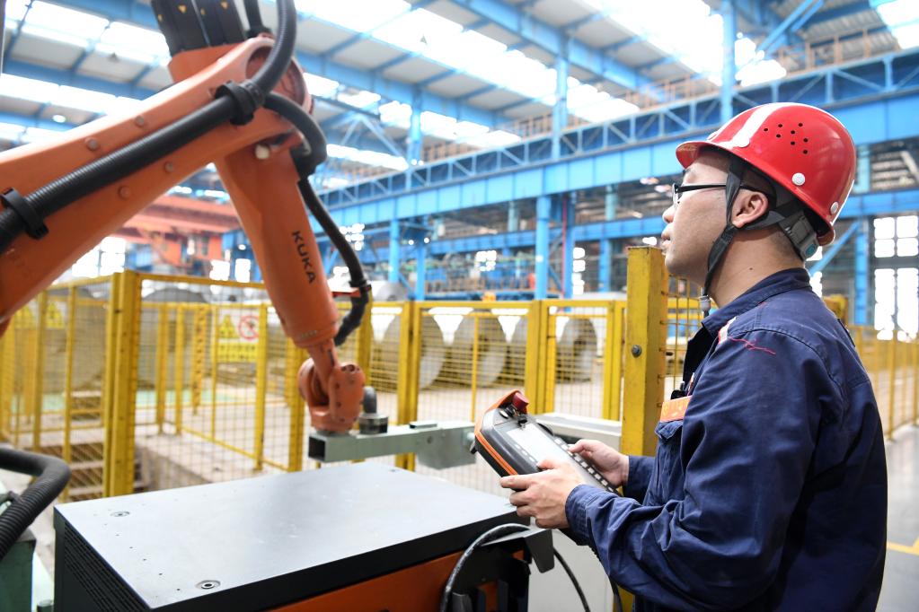 在柳钢集团冷轧厂生产车间，技术工人汤龙波检查工业机器人运行情况。（黎寒池摄）