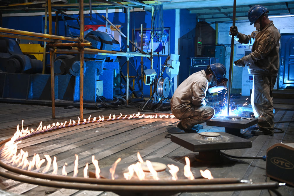 △哈电集团哈尔滨电机厂有限责任公司“80后”电焊工胡世峰（左）在冷作分厂作业（4月8日摄）。