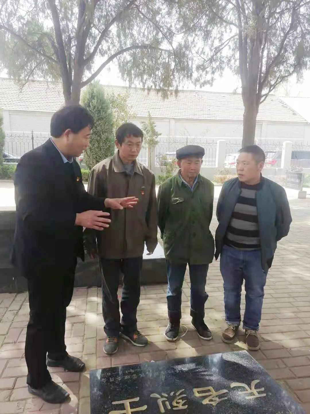 张景宪（左一）向施明山烈士家人介绍情况