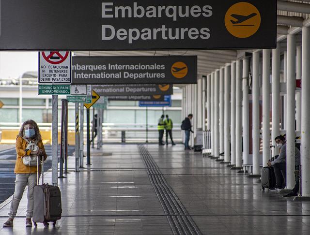 图为智利圣地亚哥机场内旅客佩戴口罩出行,机场内人迹罕至.