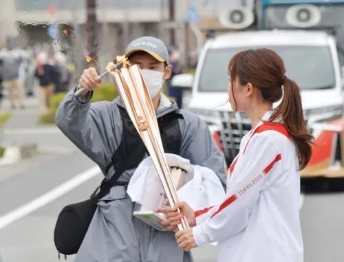 工作人员为火炬手重新点燃圣火，图源：日本《每日新闻》