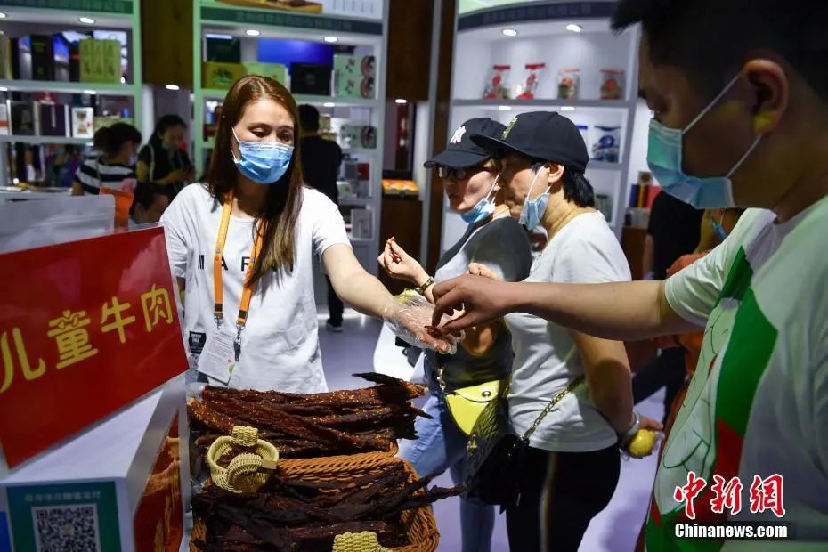 图为参观者在甘肃馆品尝牛肉干。中新社记者 崔楠 摄