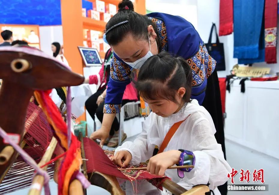 图为小朋友在湖南馆体验土家族传统织布技艺。中新社记者 崔楠 摄