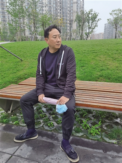 4月19日，谭乔在路边等车。新京报记者 李照 摄