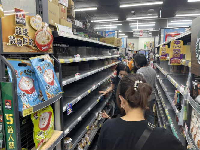 台北、新北市疫情警戒升至三级，大量民众冲入超市，抢购罐头、泡面等物资。图自台湾中时新闻网