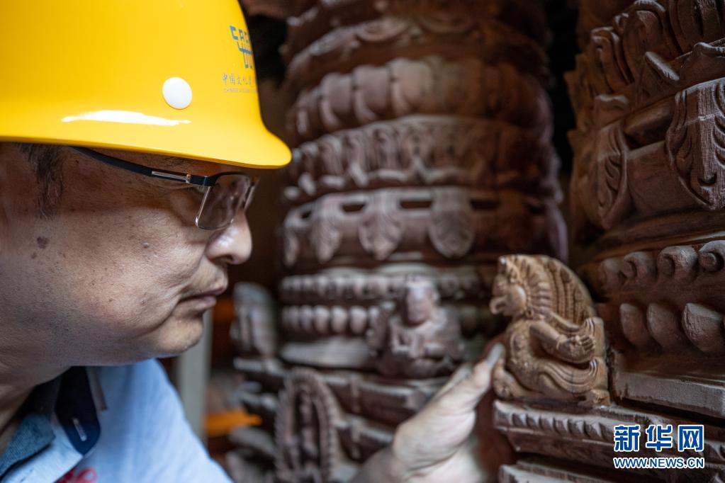 2019年10月10日，在尼泊尔加德满都杜巴广场，中国派出的文物修复队技术主管周建国在九层神庙修复现场查看一个修复好的文物。新华社记者 王婧嫱 摄